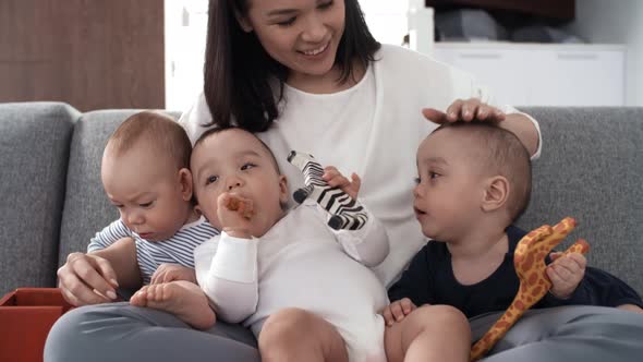 Filipino Mom Sitting on Couch with Triplets