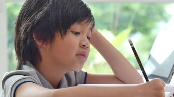 Asian Child Tired And Bored Of Doing Homework, Kid Stressed From Learning