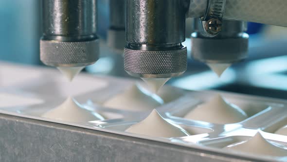 Machine Is Filling Containers with White Dairy Substance