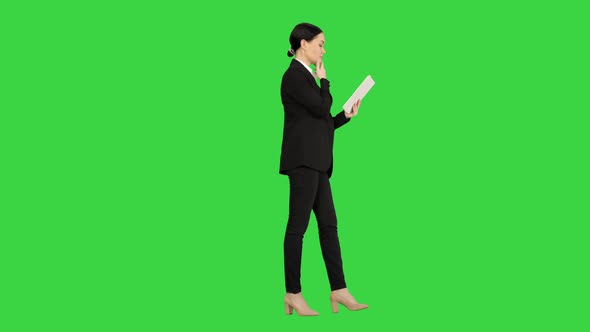 Businesswoman Using a Tablet Pad While Walking on a Green Screen, Chroma Key.