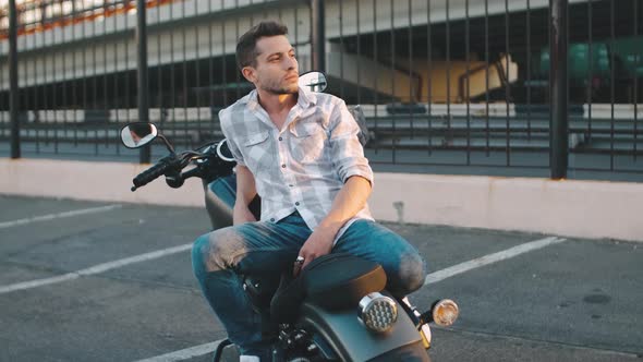 Portrait of Man Biker with Custom Motorcycle on Street at Sunset