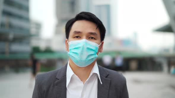 business man walking and wearing medical mask during coronavirus (covid-19) pandemic in the city
