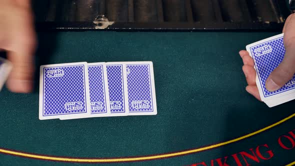 Casino Blackjack Dealer's Hands Lay Out a Deck of Playing Cards