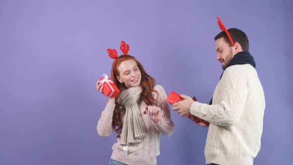 Happy Young Couple in White Sweaters Dancing of Happiness with Christmas Gifts in Their Hands.