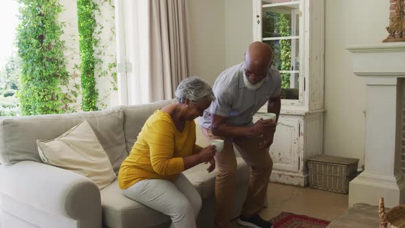 African american senior couple smiling while having coffee together sitting on the couch at home