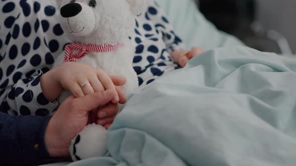 Closeup of Father Holding Daughter Hand After Suffering Medical Surgery During Sickness Recovery