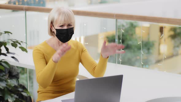 Focused Puzzled Mature Caucasian Woman in Protective Mask Typing on Laptop Upset Making Mistake