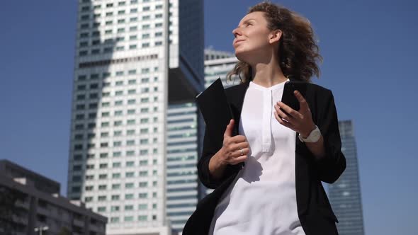 Stressed Business Woman Walking in Front of Skyscrapers