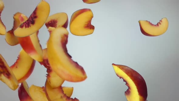 Fresh Ripe Peach Slices are Falling and Spinning on the White Background