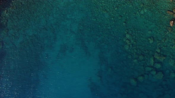 Drone flight above transparent calm azure blue water in Turkish bay; top down