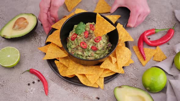 Woman Puts Nachos Chips and Freshly Made Guacamole on the Table