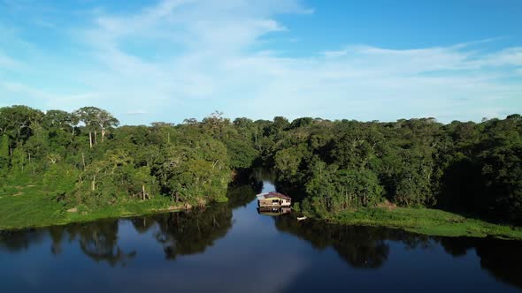 Cinematic shot of the Mighty Amazon river surrounded by tropical jungle green rainforest and a small