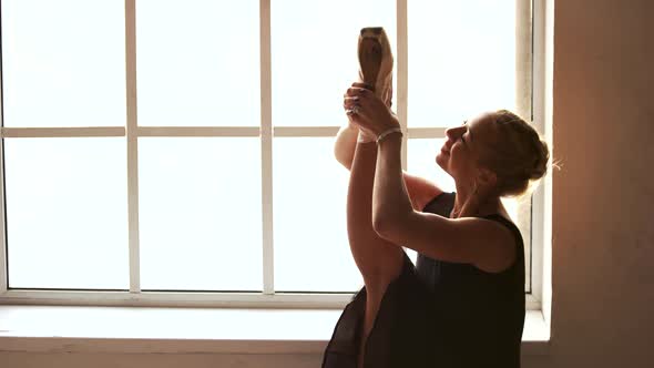 Ballet Dancer Stretching Her Leg in Studio