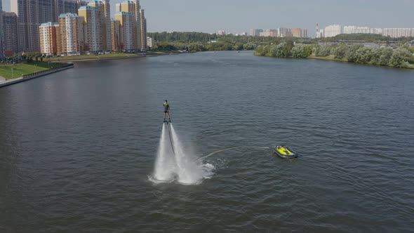 A Man Flies Over the River on a Flyboard and Dives Into the Water