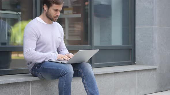 Handsome Man Working on Laptop while Sitting Outside Office