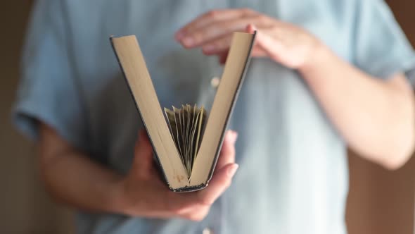 The girl opens the book and takes out a few dollar bills. The money was hidden