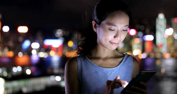 Woman use of mobile phone in Hong Kong city at night 