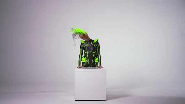 Wide Shot Portrait of Slim Flexible Woman Emerging Behind Cube at White Background Doing Back