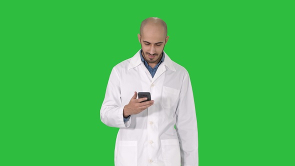 Male arab doctor texting message on the phone while walking