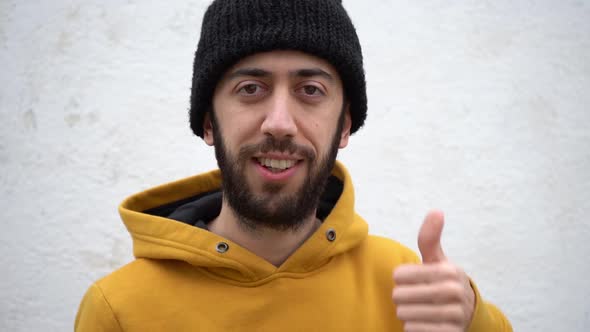 An Adult Male Doing A Thumbs Up Signal Using One Hand With A Smile On His Face. Close-up