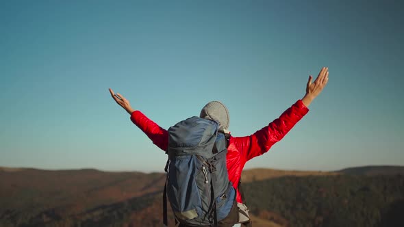 Slow Motion Rear View Young Adventurous Woman Hiker Backpacker in a Red Insulated Jacket and Jeans