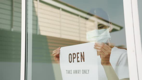 Woman owner puts a OPEN take away only sign on the front door