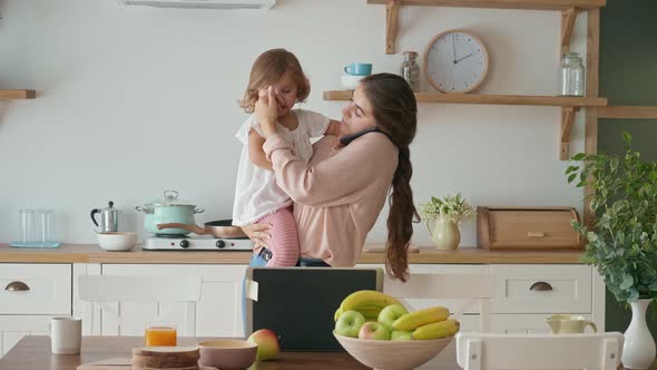 A Busy Mother Trying To Work Remotly While Holding Her Crying A Little Daughter