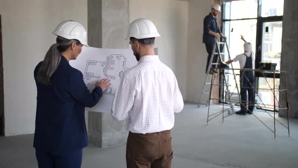 Designers Holding Blueprint with Apartment Layout