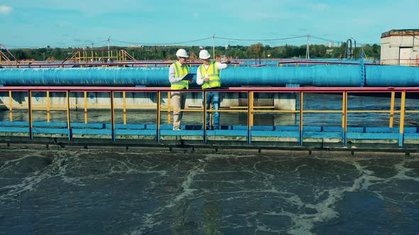Two Wastewater Treatment Operators Inspecting a Clarifier