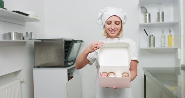 Girl Confectioner In White Hat And Apron Holding Box With Tasty Colorful