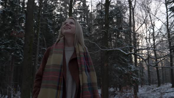 Beautiful woman in coat and scarf in snow forest