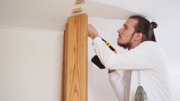 the Carpenter Screws with a Screwdriver Wooden Ash Lamellae to the Ceiling