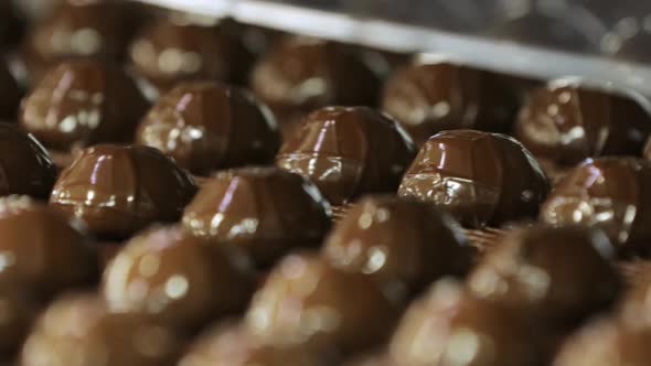 A Lot of Sweets on the Conveyor Doused with Dark Chocolate