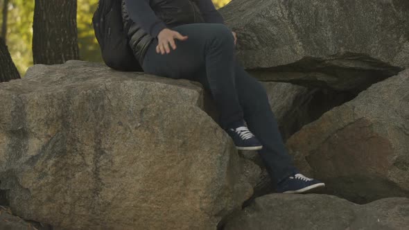 Smiling Young Man Sitting on Big Stones, Camping in Wild, Enjoying Adventure