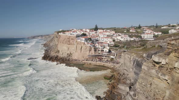 Pull out shot along the shore at Azenhas Do Mar capturing wild ocean waves hitting on the cliff.