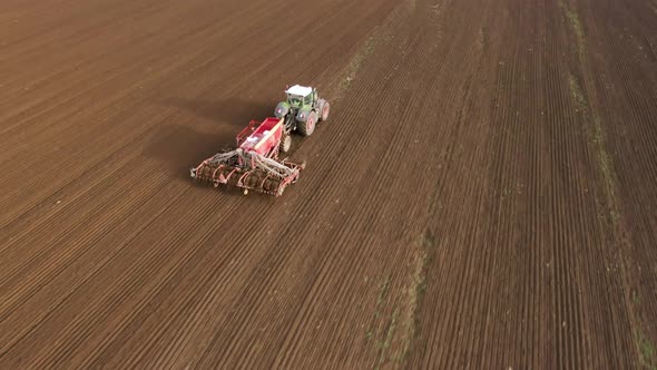 Tractor in Working in the Field. Tractor with a Modern Sowing Seeds Machine in a Newly Plowed Field