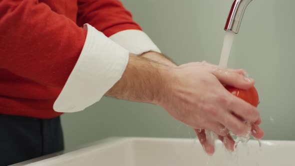 A person washes a tomato