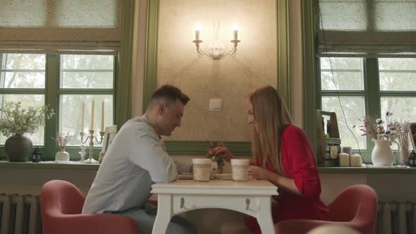 A Man and a Beautiful Young Girl are Sitting at a Table in a Vintage Cafe are Laughing and Looking