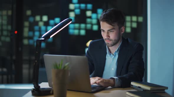 Young Businessman Man Sits at a Desk in the Office and Works on a Laptop Manager Makes a Successful