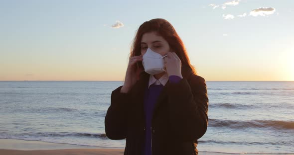 Girl on the Beach at Sunrise Sea Puts on the Ffp2 Mask