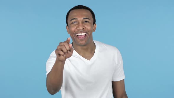 African Man Pointing at Camera Blue Background alt