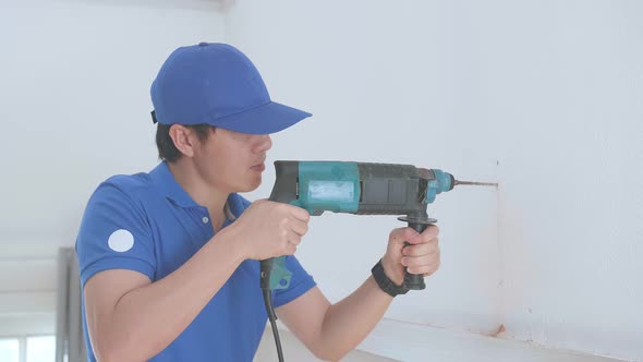 Asian Man Technician Worker Use Electric Drill On Wall In Him House, Home Improvement And Repairs