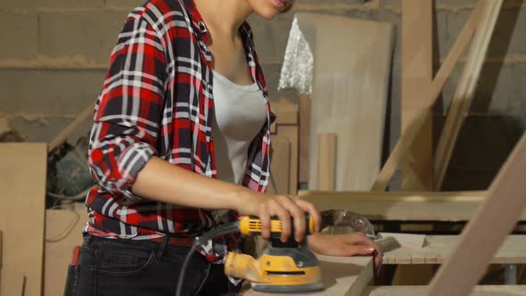 Female Carpenter Sanding Wood at Her Workshop