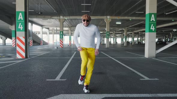 Cheerful and Happy Young Man with Beard Actively Is Dancing While Walking Down the Street on Urban