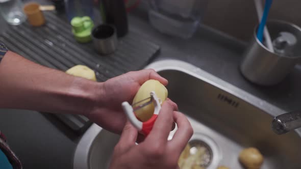 A Man Peels Potatoes with a Special Vegetable Peeler