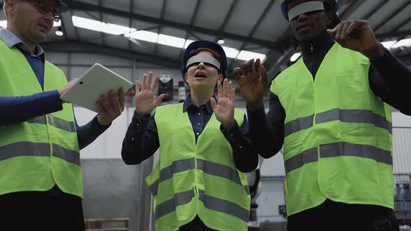 Team of engineers having simulation experience with virtual reality glasses inside robotic factory