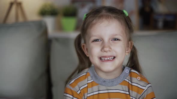 Little Girl Child Sitting On Sofa At Home