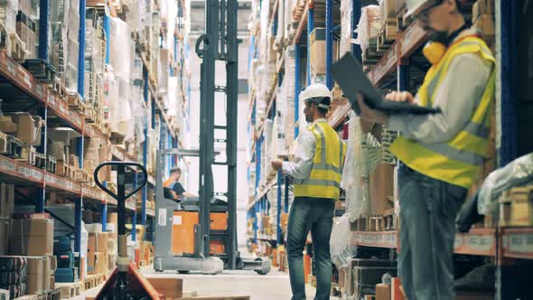 Warehouse Hall with a Loading Machine and Male Workers