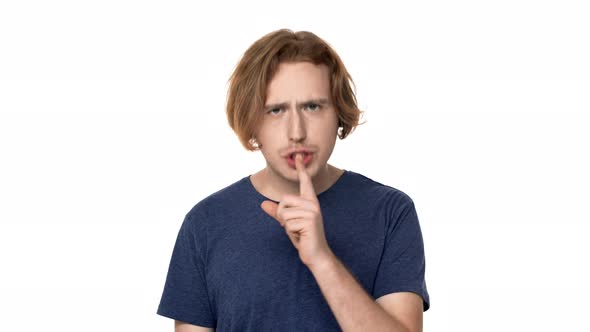 Portrait of Unshaved Guy Posing with Strict Gaze and Asking Keep Quiet Putting Index Finger on Lips