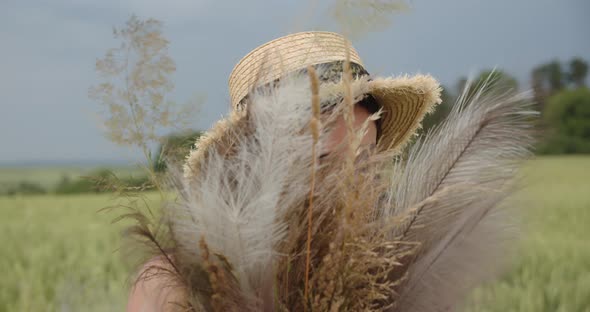 Girl In A Field In A Straw Hat Caresses Herself With A Featherbed